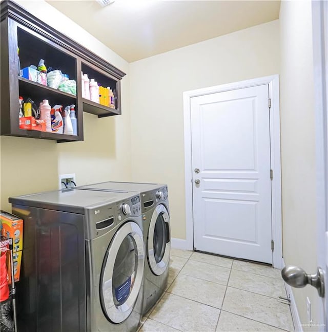 clothes washing area featuring washer and clothes dryer and light tile patterned floors