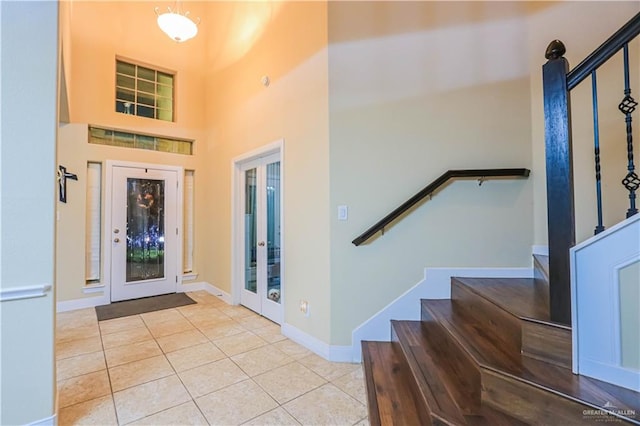 foyer entrance with light tile patterned floors, a high ceiling, and french doors