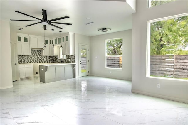 kitchen with white cabinets, a center island, backsplash, and a wealth of natural light