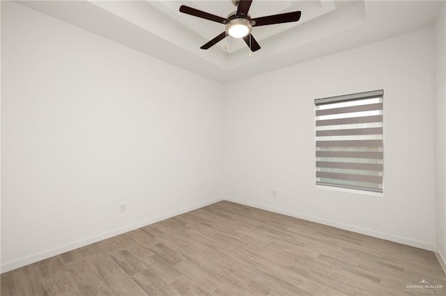 unfurnished room featuring light hardwood / wood-style floors, a raised ceiling, and ceiling fan