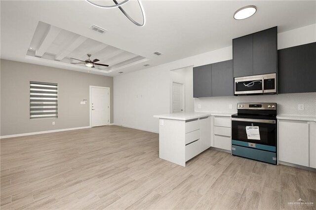 kitchen featuring appliances with stainless steel finishes, a raised ceiling, ceiling fan, white cabinets, and light hardwood / wood-style floors