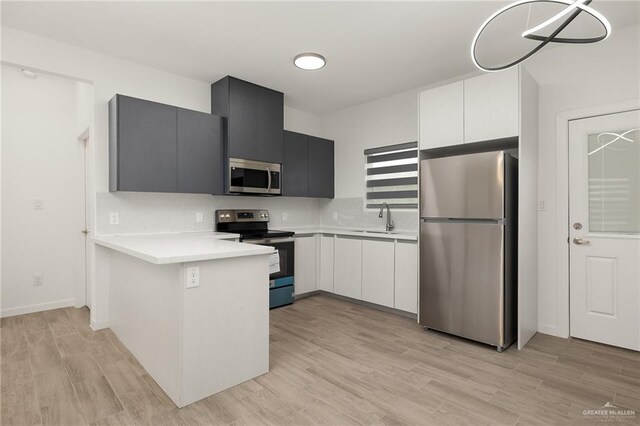 kitchen featuring stainless steel appliances, white cabinetry, light hardwood / wood-style floors, and sink