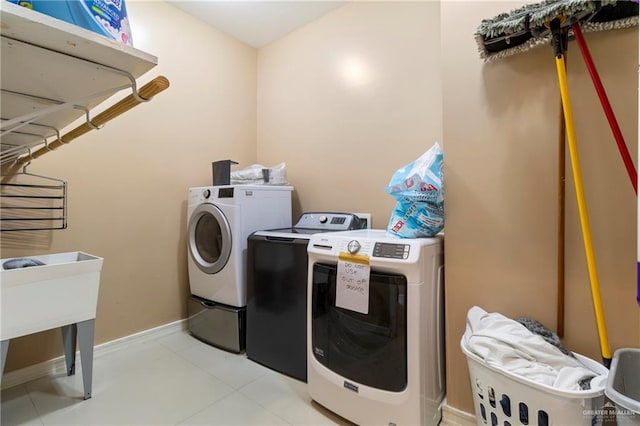 clothes washing area featuring light tile patterned floors, sink, and washer and dryer