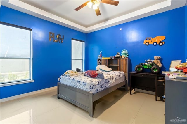 tiled bedroom featuring ceiling fan and a raised ceiling