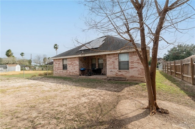 318 Lunar Dr, Donna, TX 78537 - rear view of house featuring brick siding, solar panels, roof with shingles, a fenced backyard, and a patio area