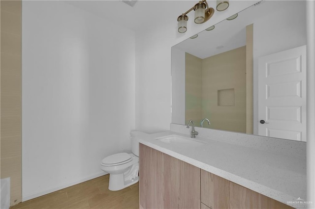 bathroom with toilet, wood finished floors, and vanity