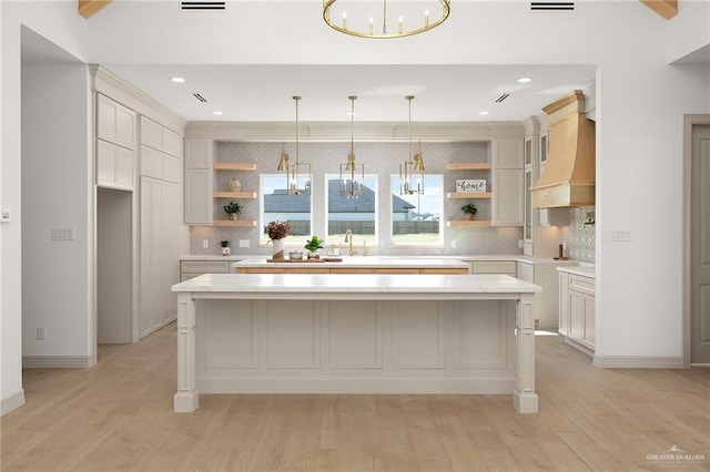 kitchen featuring light hardwood / wood-style floors, hanging light fixtures, a kitchen island, and a notable chandelier