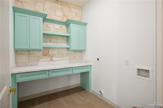 kitchen featuring light hardwood / wood-style flooring, green cabinets, light stone counters, built in desk, and decorative backsplash