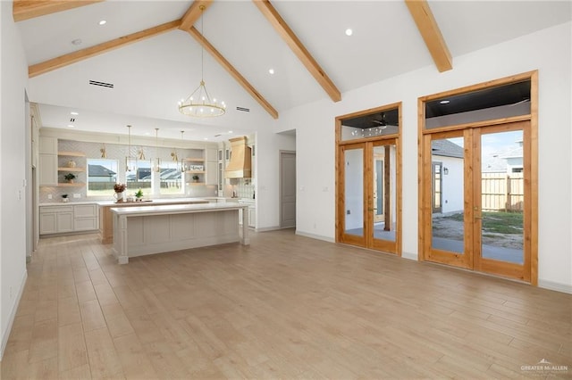 kitchen with premium range hood, pendant lighting, high vaulted ceiling, a center island, and an inviting chandelier