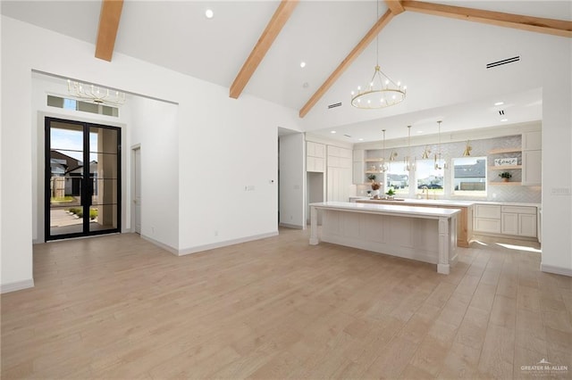 kitchen featuring beam ceiling, high vaulted ceiling, a large island, and an inviting chandelier