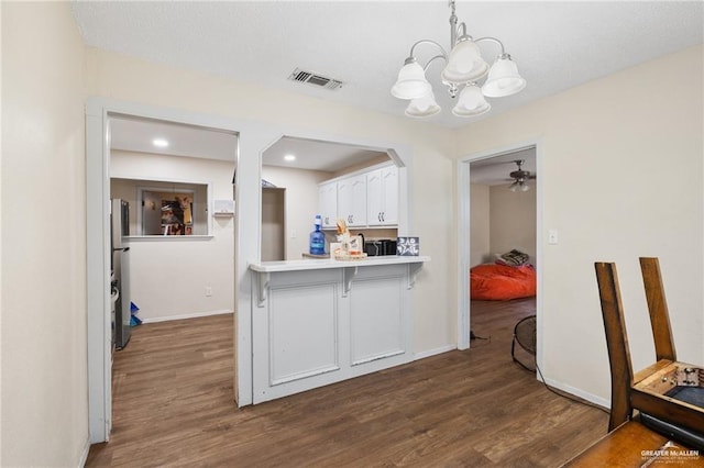 kitchen with hanging light fixtures, kitchen peninsula, dark hardwood / wood-style flooring, white cabinetry, and ceiling fan with notable chandelier