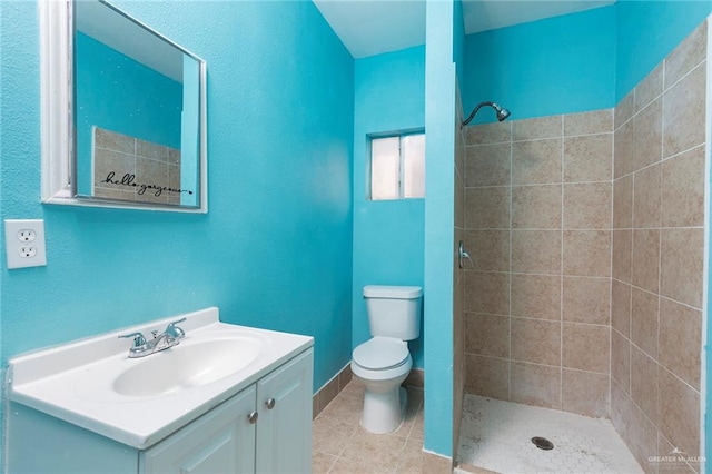 bathroom featuring tile patterned floors, vanity, toilet, and tiled shower