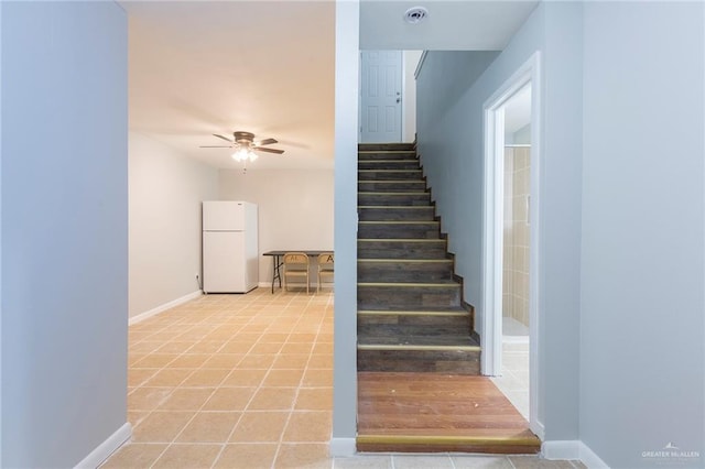 staircase featuring tile patterned flooring and ceiling fan