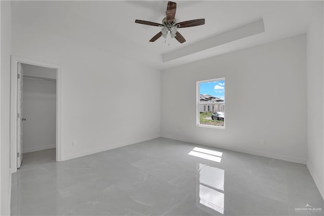 spare room featuring a raised ceiling and ceiling fan