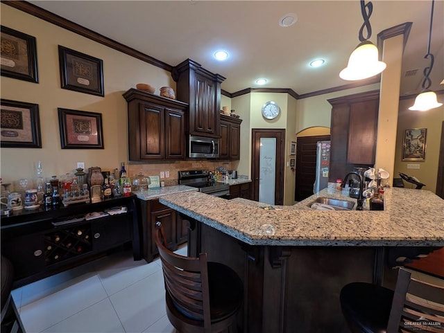 3300 Harding Ave, Alton, TX 78573 - kitchen featuring appliances with stainless steel finishes, a sink, ornamental molding, a breakfast bar, and dark brown cabinetry