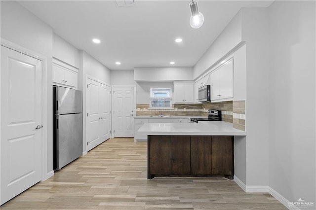 2008 Taft St, Weslaco, TX 78599 - kitchen featuring stainless steel appliances, a sink, light countertops, light wood-style flooring, and a peninsula