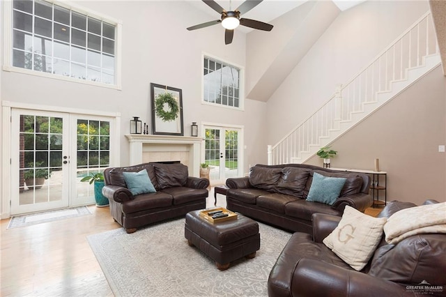 living room with hardwood / wood-style floors, a healthy amount of sunlight, a towering ceiling, and french doors