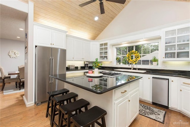 kitchen with white cabinets, a center island, high end fridge, and light hardwood / wood-style flooring