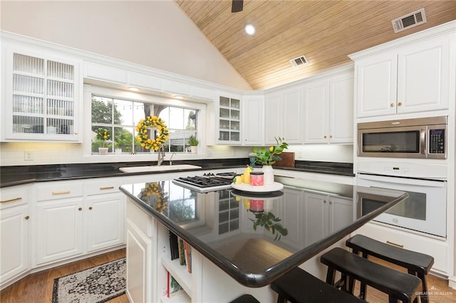 kitchen featuring white cabinets, a kitchen bar, stainless steel appliances, and wooden ceiling