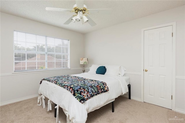 carpeted bedroom featuring ceiling fan and a textured ceiling