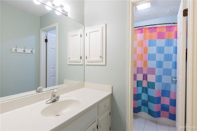 bathroom with curtained shower, tile patterned flooring, vanity, and a textured ceiling