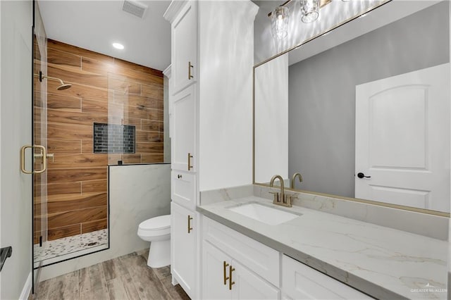 bathroom with hardwood / wood-style flooring, vanity, a shower with shower door, and toilet