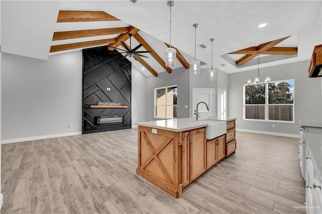 kitchen featuring sink, hanging light fixtures, a center island with sink, light hardwood / wood-style floors, and white cabinets