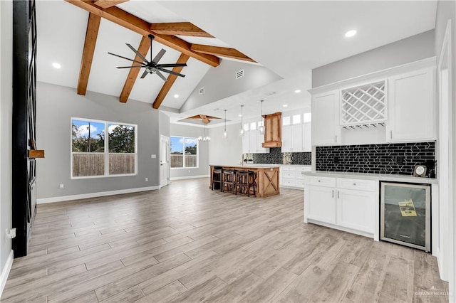 kitchen featuring a spacious island, wine cooler, white cabinetry, hanging light fixtures, and backsplash