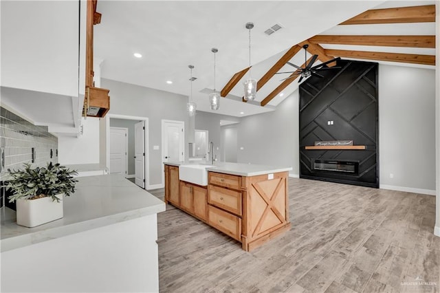 kitchen featuring sink, hanging light fixtures, a kitchen island with sink, ceiling fan, and light hardwood / wood-style floors