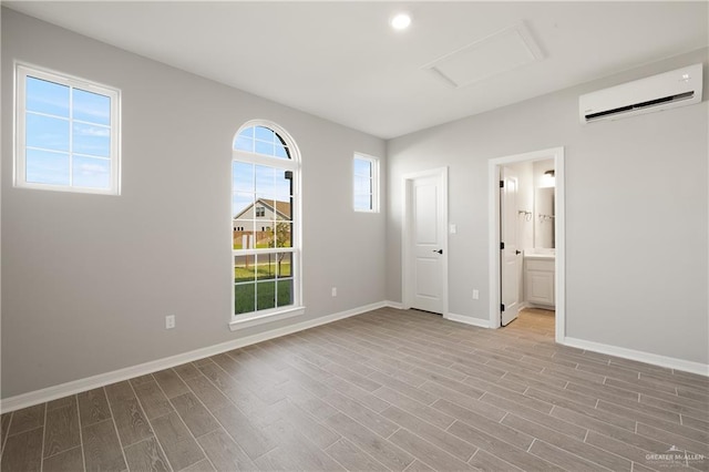 spare room with a wall unit AC and light hardwood / wood-style floors