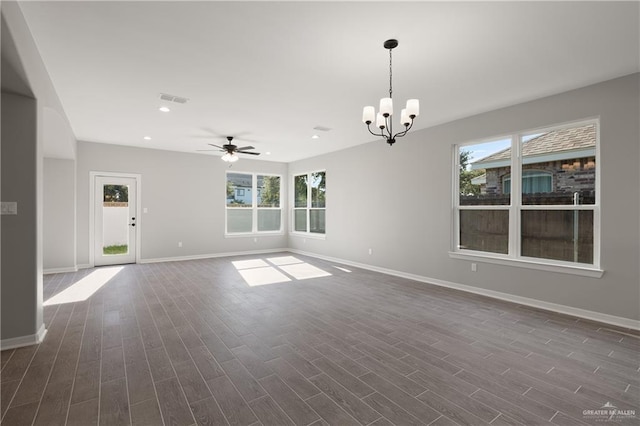 spare room featuring ceiling fan with notable chandelier