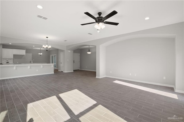 unfurnished living room featuring ceiling fan with notable chandelier