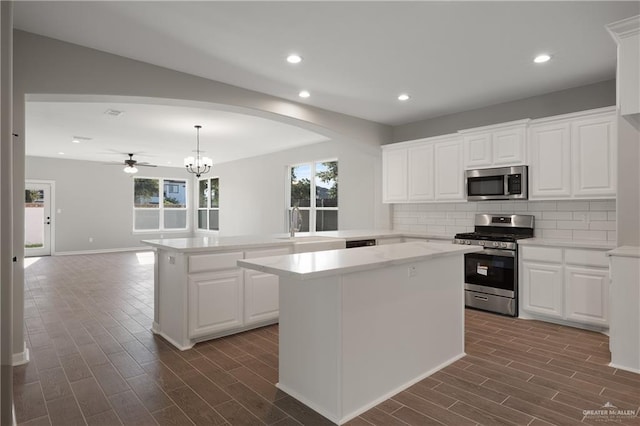 kitchen featuring appliances with stainless steel finishes, white cabinetry, decorative backsplash, a center island, and kitchen peninsula