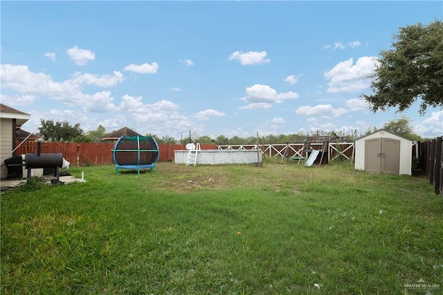 view of yard with a trampoline, a storage unit, and a fenced in pool