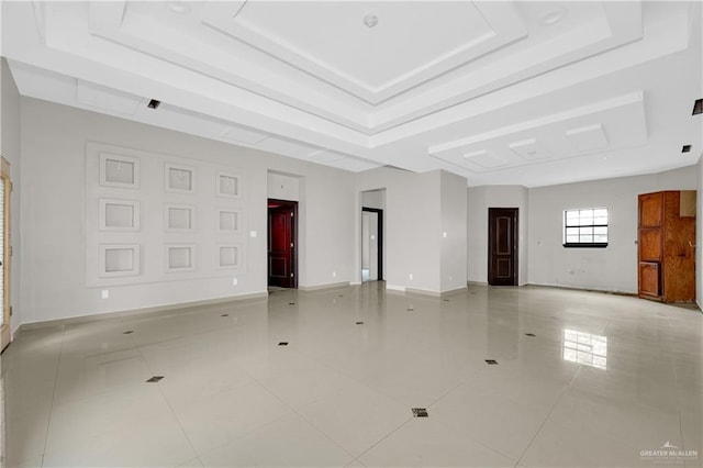 interior space featuring a tray ceiling, baseboards, and light tile patterned floors