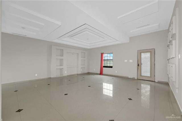 tiled empty room with baseboards and a raised ceiling