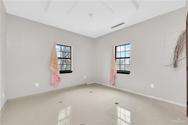 tiled empty room featuring visible vents and baseboards