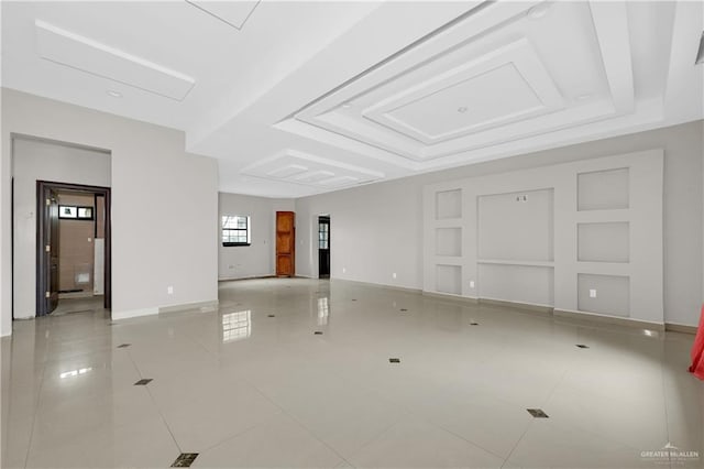 empty room featuring a tray ceiling, light tile patterned flooring, and baseboards