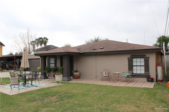 back of property featuring a patio, a garage, a lawn, roof with shingles, and stucco siding