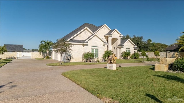 french country home featuring concrete driveway, stone siding, a front lawn, and a garage