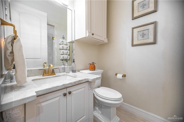 bathroom with toilet, baseboards, and vanity