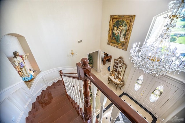 stairs featuring a chandelier, wood finished floors, and a high ceiling