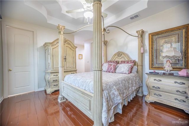 bedroom with hardwood / wood-style flooring, a raised ceiling, a ceiling fan, and visible vents