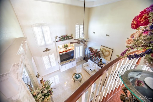 living room with ceiling fan, visible vents, a fireplace, and a high ceiling