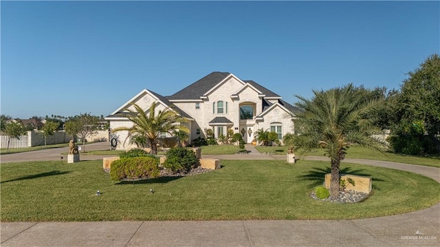 traditional home with a front yard, curved driveway, and stone siding
