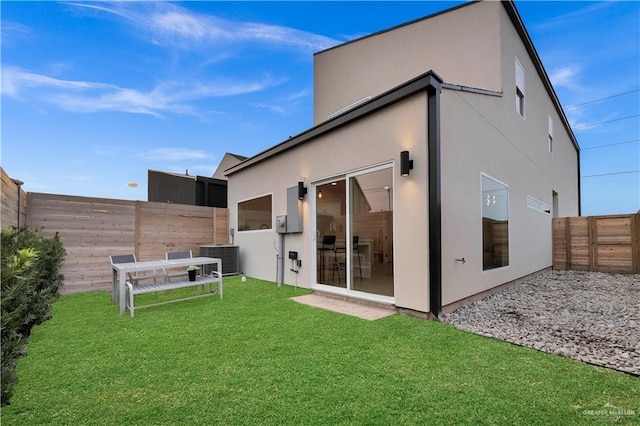 back of house featuring a fenced backyard, stucco siding, a yard, and central AC unit