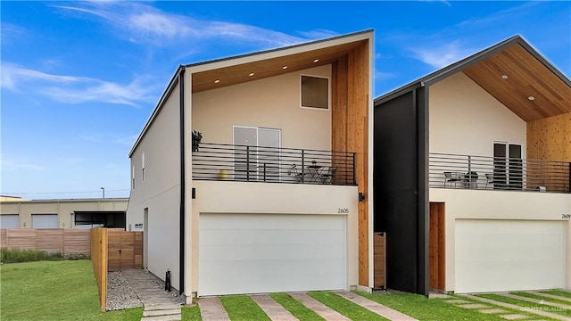 back of house featuring fence, stucco siding, an attached garage, and a balcony