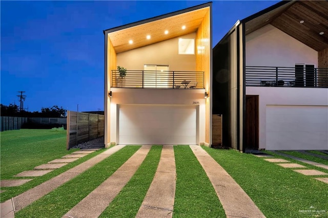 contemporary house with stucco siding, fence, a balcony, and a front yard