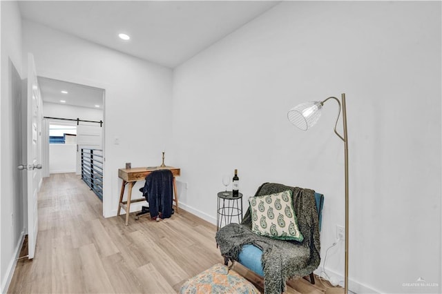 sitting room featuring baseboards, a barn door, wood finished floors, and recessed lighting