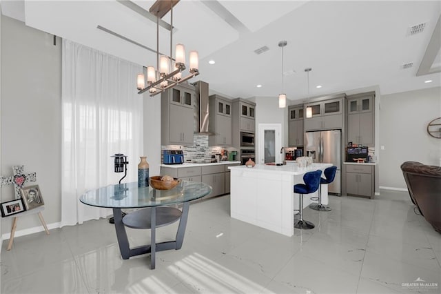 2000 Providence Ave, Mcallen, TX 78504 - kitchen with gray cabinets, appliances with stainless steel finishes, wall chimney range hood, decorative backsplash, and a kitchen breakfast bar